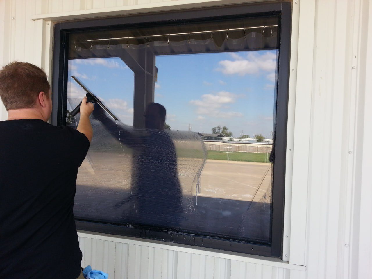 Window cleaner squeegeeing a commercial window from outside